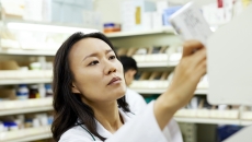 Pharmacist in a pharmacy looking at a piece of paper while holding it up to the light