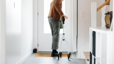 A senior adult using a walker opening a door