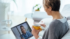 Woman interacting with healthcare professional via laptop 