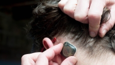 A person pulling back their hair to place the sensor
