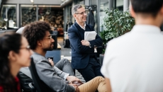 Numerous people sitting in a courtyard and looking at something off camera