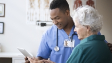 Healthcare provider and a patient standing next to each other both looking at a tablet