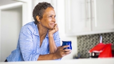 Person leaning against a counter holding a coffee cup