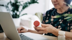 Person looking at a prescription bottle while on a computer