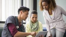 A doctor showing a patient and a family member information on a tablet.
