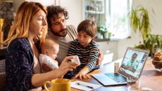 A family talking to a doctor through a video chat on a laptop.
