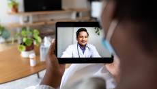 Person holding up a tablet with a telehealth provider on the screen