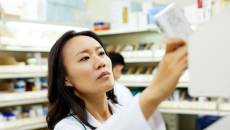 A pharmacist pulling a medication off a shelf.