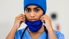 Doctor wearing blue scrubs and holding their face mask