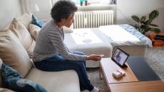 Person sitting on their couch speaking to a healthcare provider on a tablet