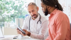 Healthcare provider sitting next to a person while both are looking at a tablet