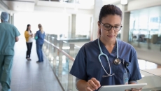 Healthcare provider looking at a tablet in the hallway of a large building