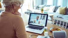 Person sitting at computer talking with person in lab coat