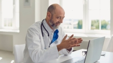 Healthcare provider sitting at a desk while looking at a laptop