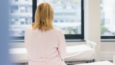 A photo of a woman sitting on a hospital bed