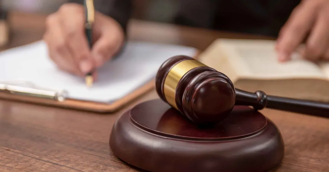 Person signing a document with a gavel on the table