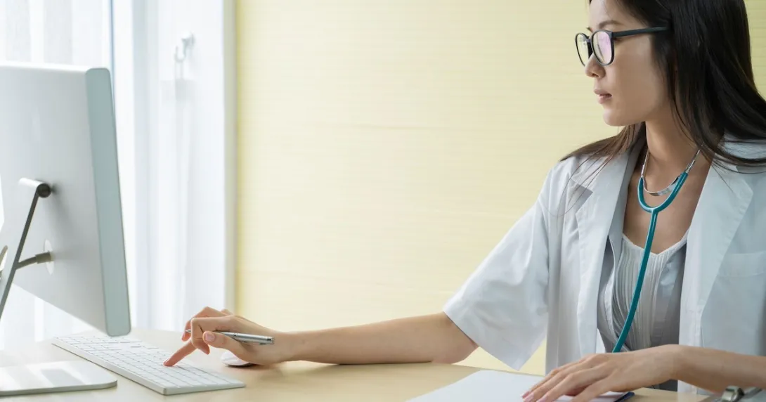 Healthcare provider sitting at a desk while looking at a computer