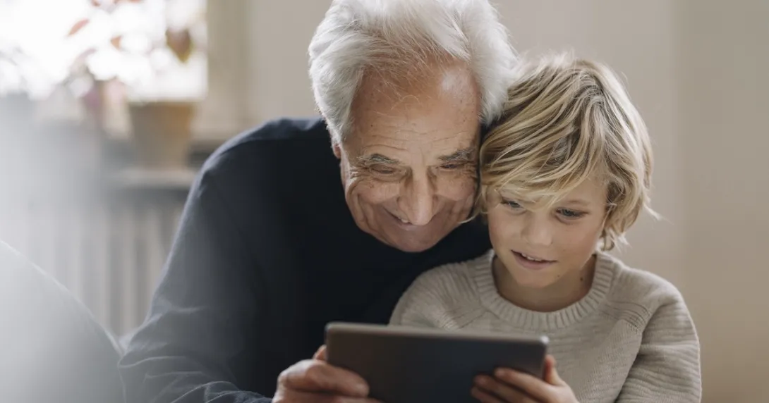 Older man looking at a tablet computer with a young boy
