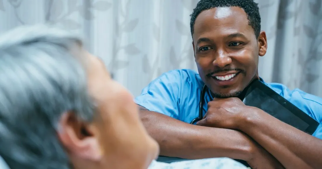 Healthcare provider sitting at a patient's bedside