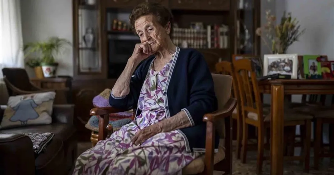 Older woman sitting in her living room pensive and depressed