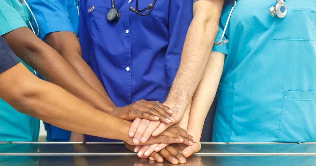 Healthcare providers putting their hands together in unification