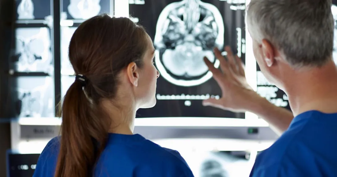 Two healthcare providers looking at a diagnostic image of a brain