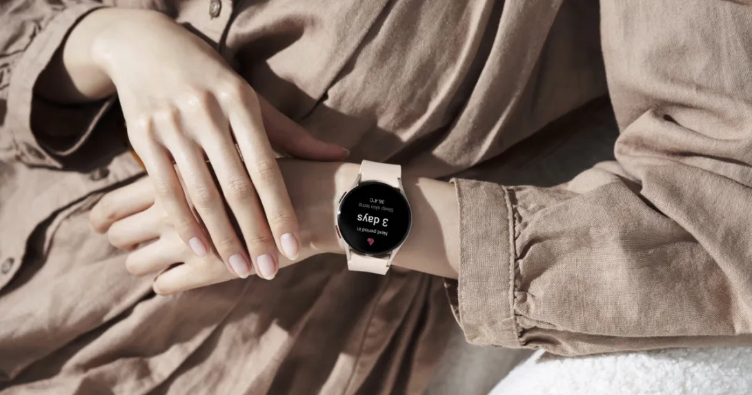 A person wearing a Samsung Galaxy Watch5 displaying a period prediction.