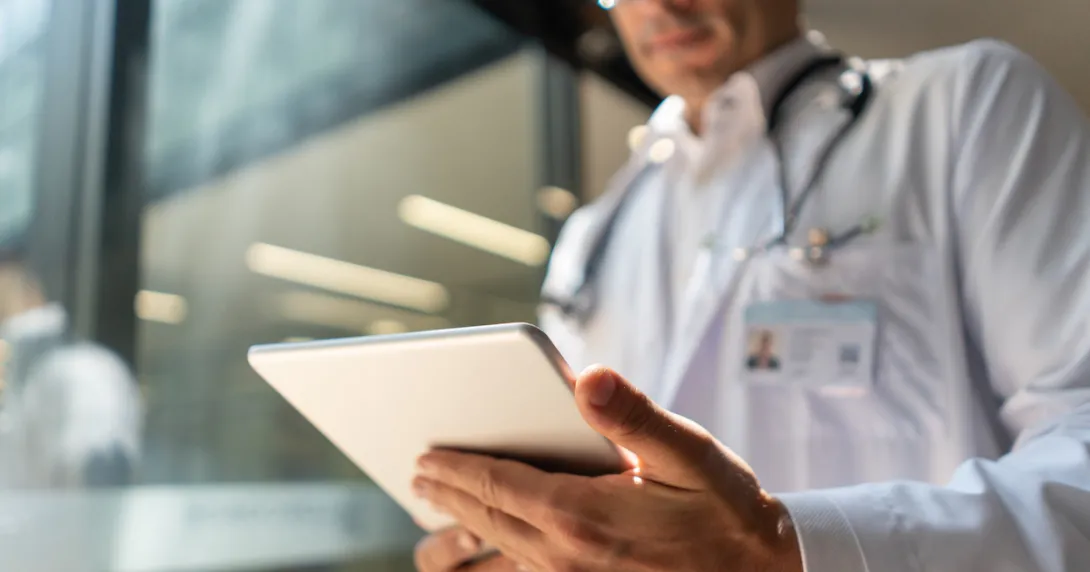 A doctor holding a digital tablet reviewing a patient's record