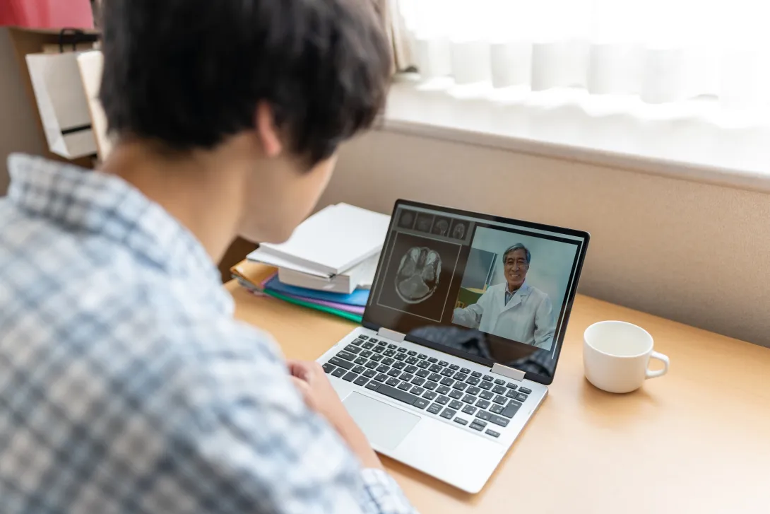 A person video chatting with a doctor on a laptop.