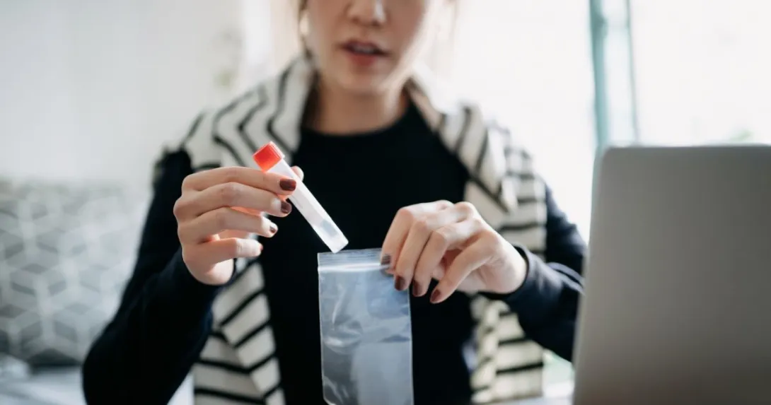 person with vial in front of computer monitor