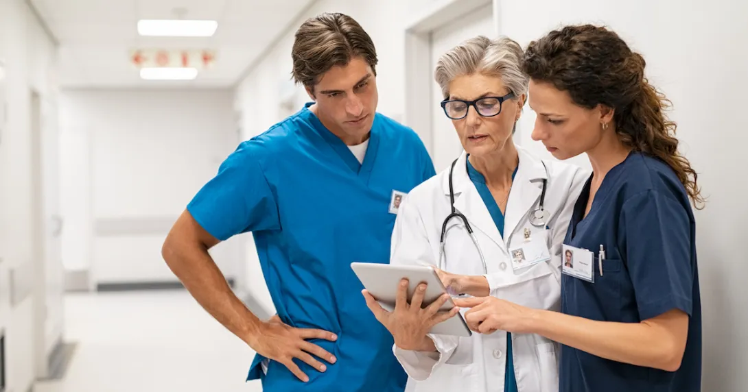 Healthcare providers standing in the hallway of a hospital looking at a tablet