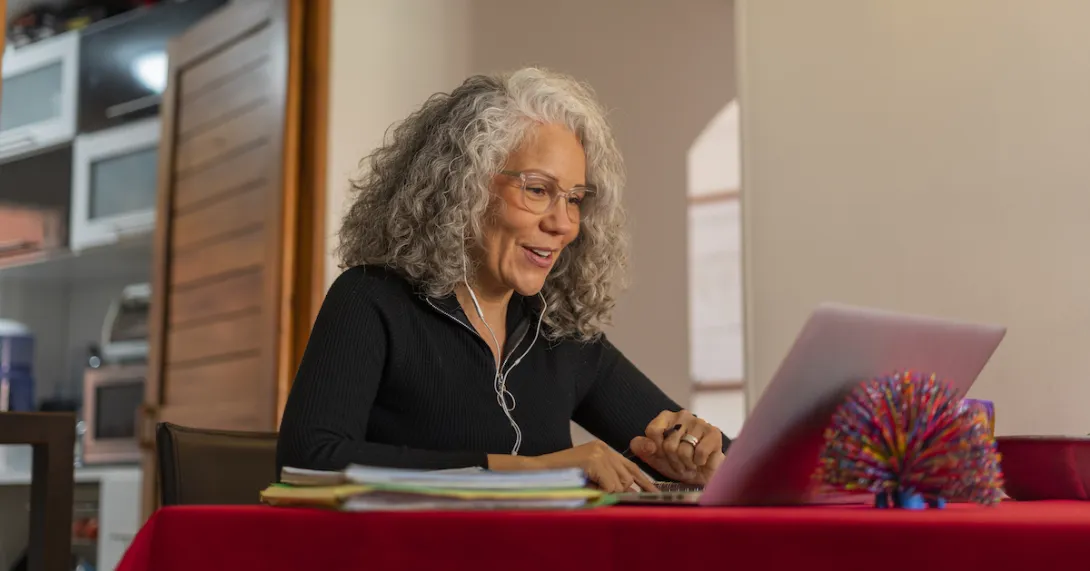 Person sitting at a dining room table looking at a computer
