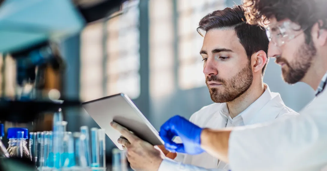 Two scientists in a laboratory looking at a tablet