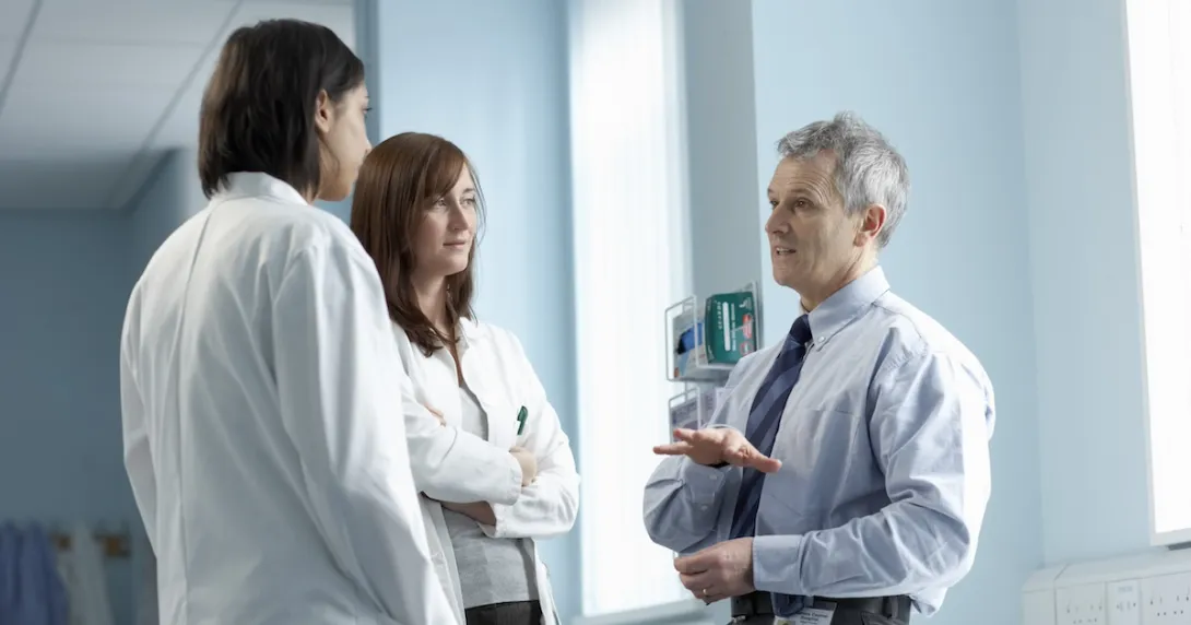 Three healthcare professionals standing in a clinical setting