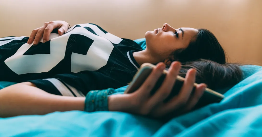 Person lying on a bed while holding a phone