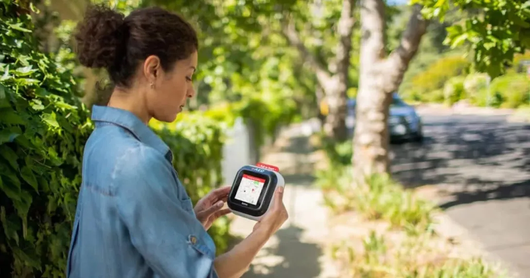 A woman holding the Avive device that is displaying a map