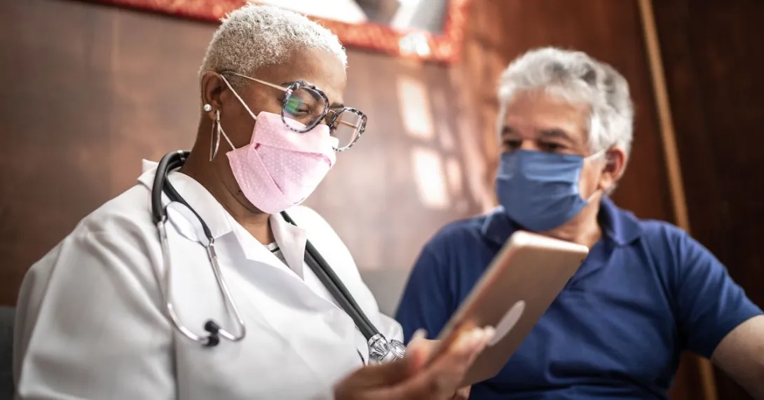 A doctor talking to a patient while holding a tablet.