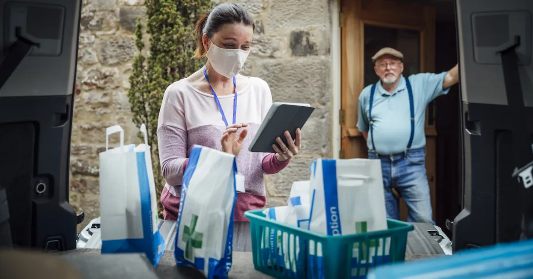 A man waiting in a doorway as a woman delivers medications