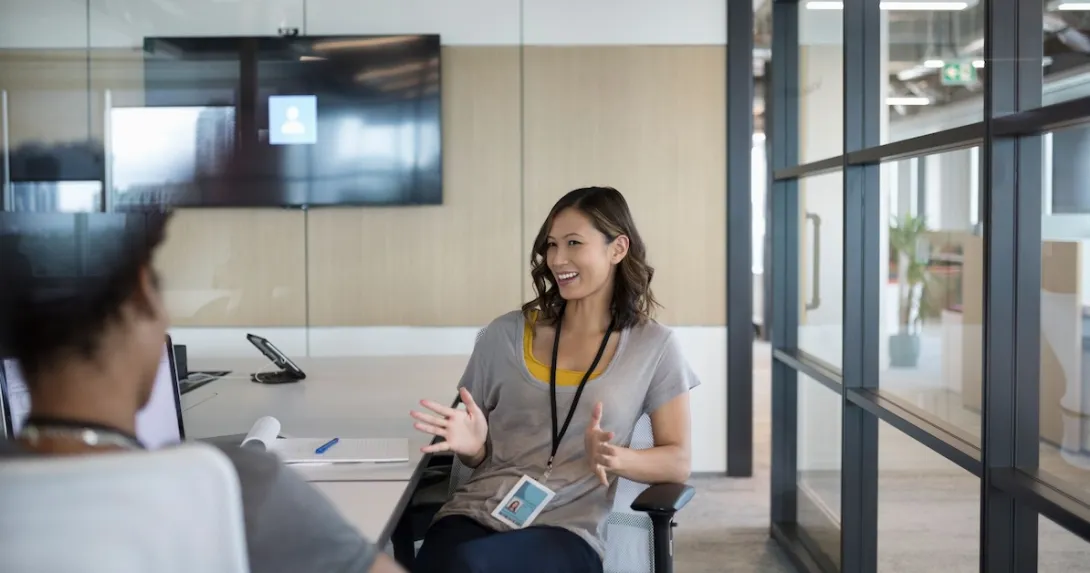 Two people sitting at a tablet talking to each other