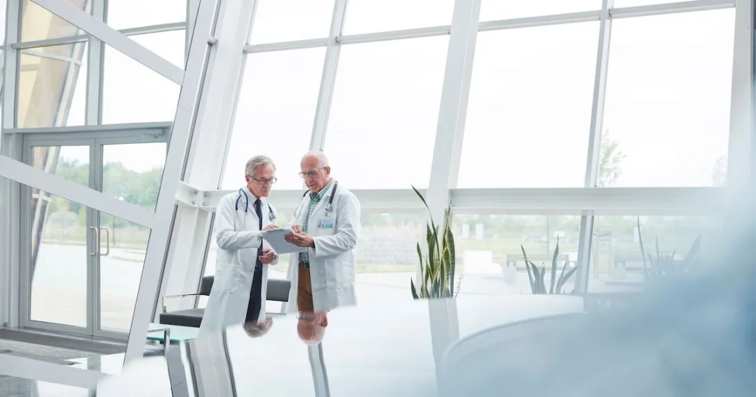Two healthcare providers in a room with big windows