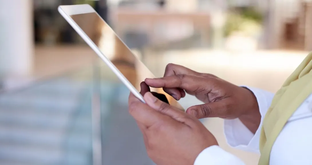 Person holding a tablet while wearing a white outfit with a yellow scarf
