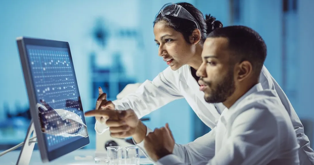 Two healthcare providers sitting in front of a computer touching the screen