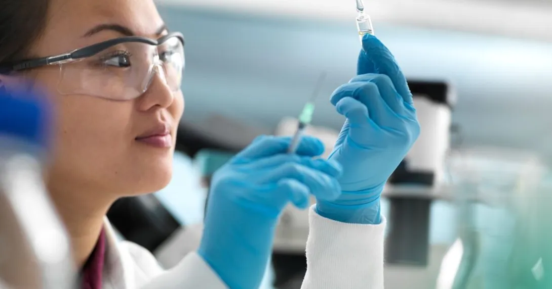 A researcher holding an injection and a vial of drug