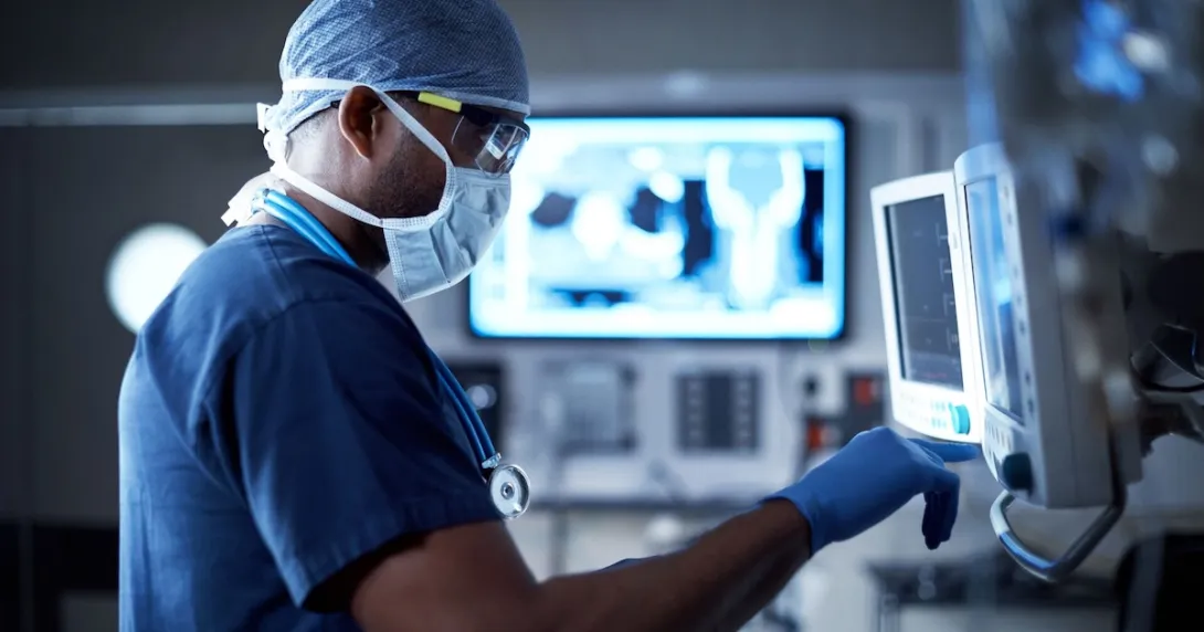 Doctor in scrubs standing in front of computer screens
