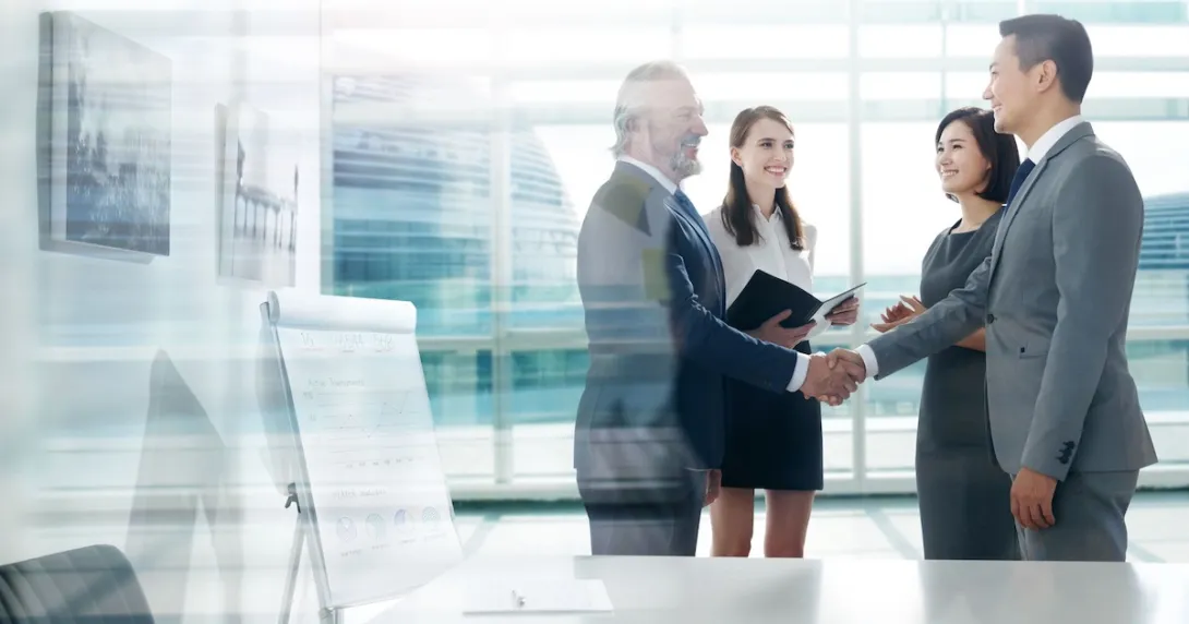 Four people standing in a room with two of them shaking hands