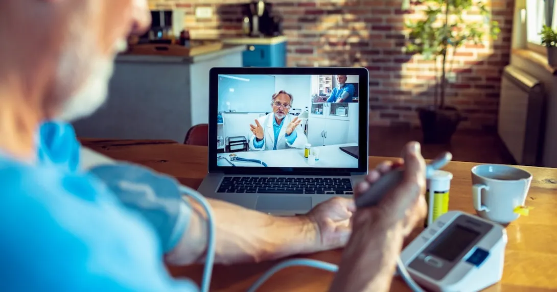 A doctor on screen guiding a patient measuring their blood pressure remotely
